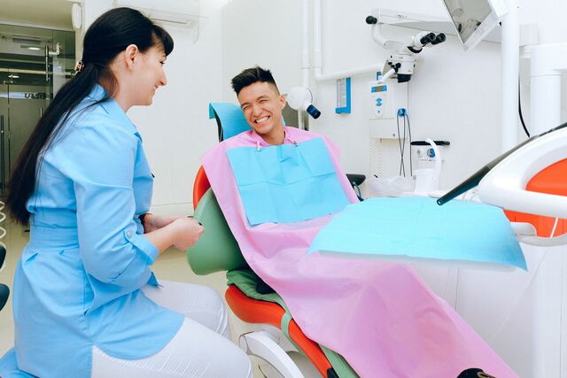 a man relaxes in a dentist chair while a dentist prepares for his dental check-up